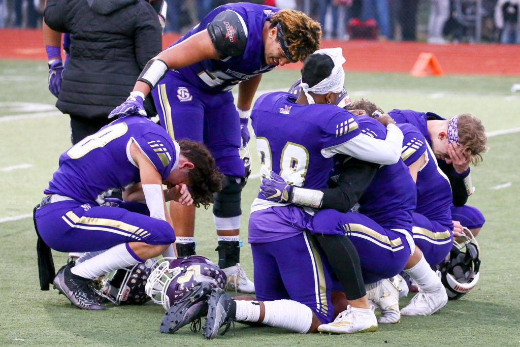 Lake Stevens players comfort one another on the field after the season-ending loss. (Kevin Clark / The Herald)
