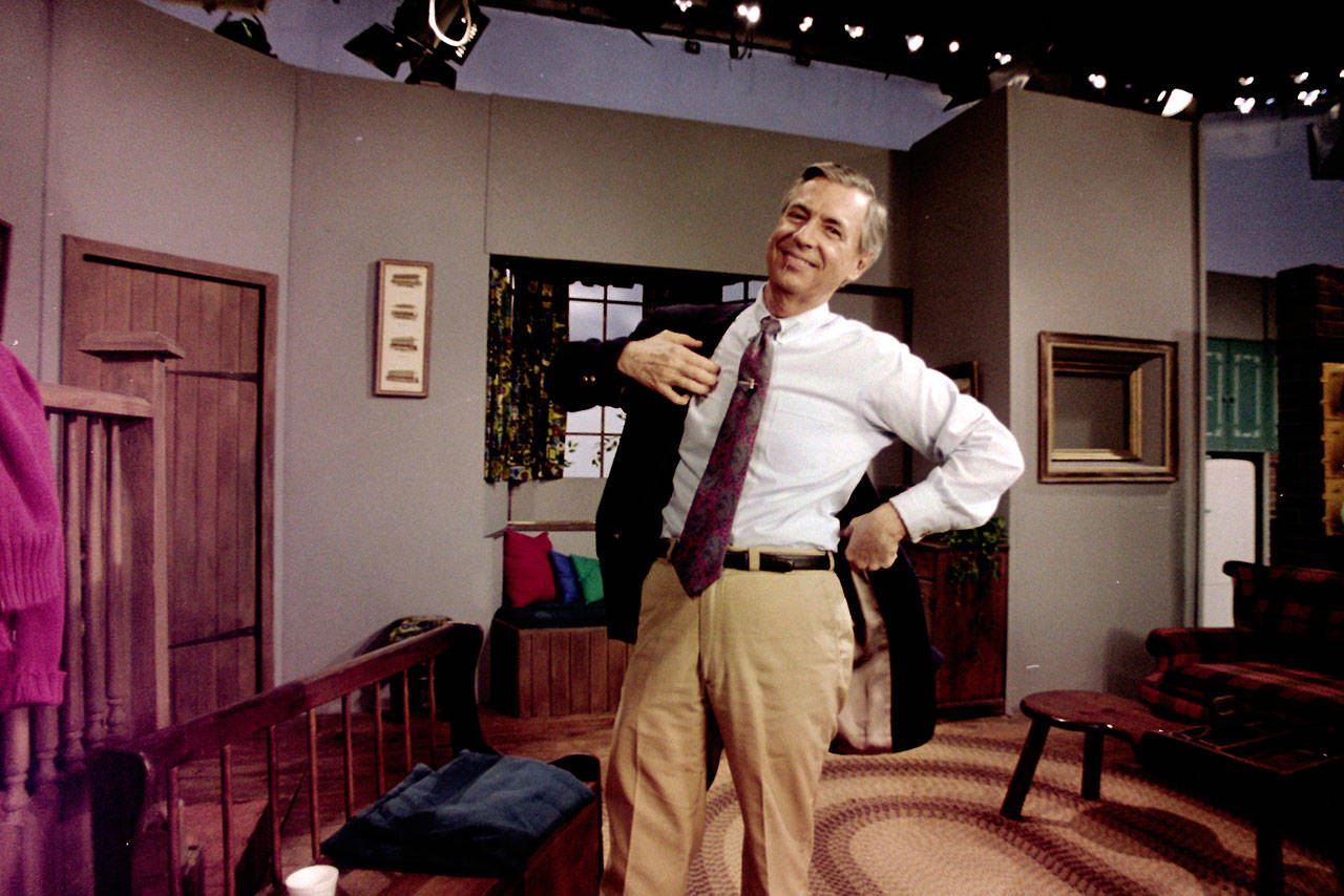 Fred Rogers puts on his jacket between takes on the set of his television program “Mister Rogers’ Neighborhood” in Pittsburgh on June 8, 1993. (Gene J. Puskar / Associated Press file photo)