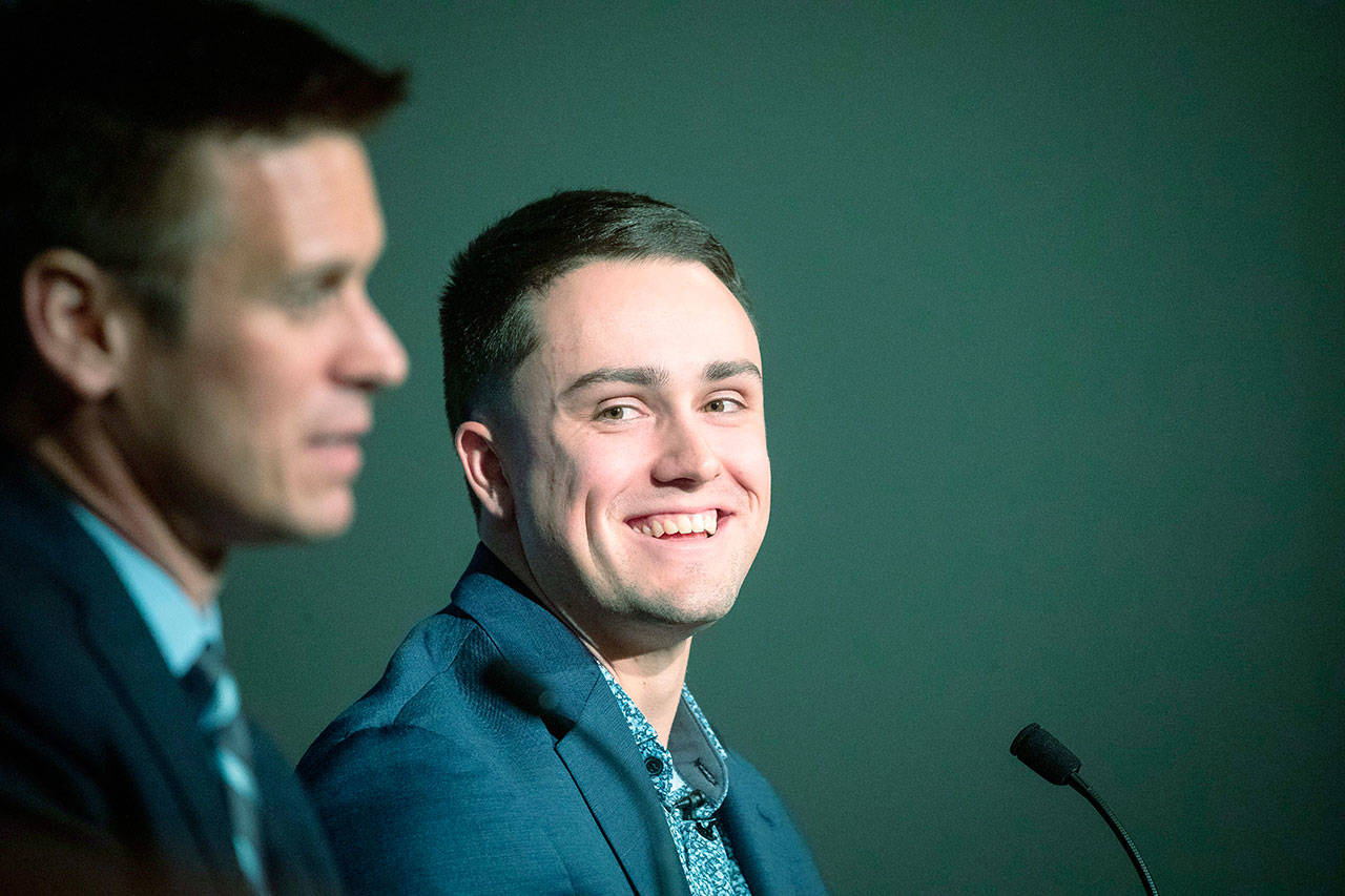 Seattle’s Evan White (right) listens as general manager Jerry Dipoto speaks during a news conference announcing the signing of White’s six-year contract on Monday at T-Mobile Park in Seattle. (Andy Bao/The Seattle Times via AP)