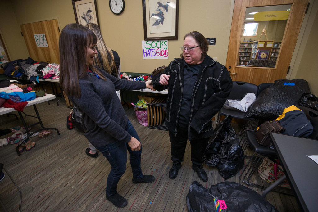 Angel Resource Connection director Penelope Protheroe, left, admires a jacket that Janice Fraser found during the nonprofit’s Winter Clothes Giveaway on Wednesday in Granite Falls. (Andy Bronson / The Herald)
