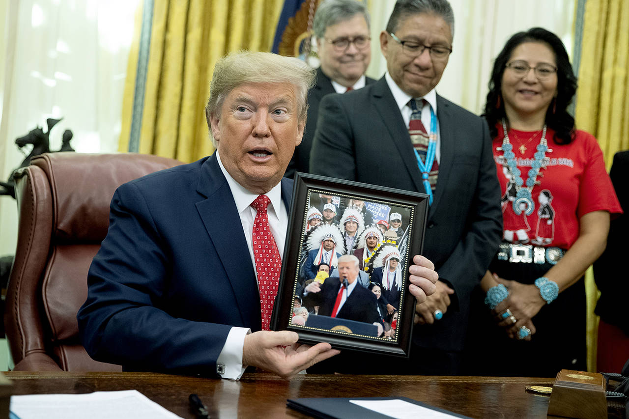 President Donald Trump shows off a gift during and event to sign an executive order establishing the Task Force on Missing and Murdered American Indians and Alaska Natives, in the Oval Office of the White House on Tuesday. (AP Photo/ Evan Vucci)
