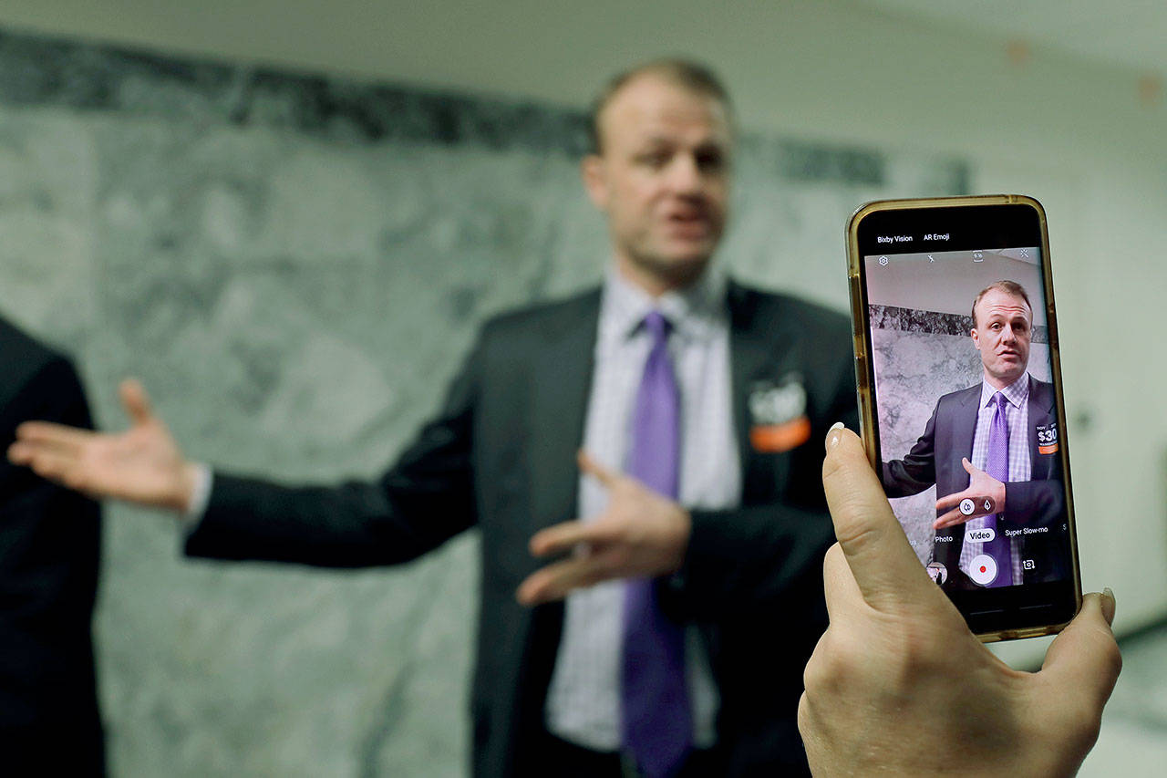 Tim Eyman, a career anti-tax initiative promoter, is recorded as he talks to reporters during a break in a King County Superior Court hearing on Tuesday in Seattle. (AP Photo/Ted S. Warren)