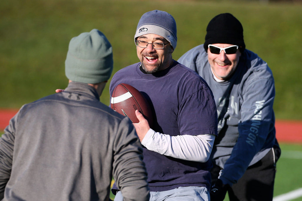 Kevin Sullivan (center) is touched down by Jason Carman (right) Saturday morning at Cascade High School in Everett. (Kevin Clark / The Herald)

