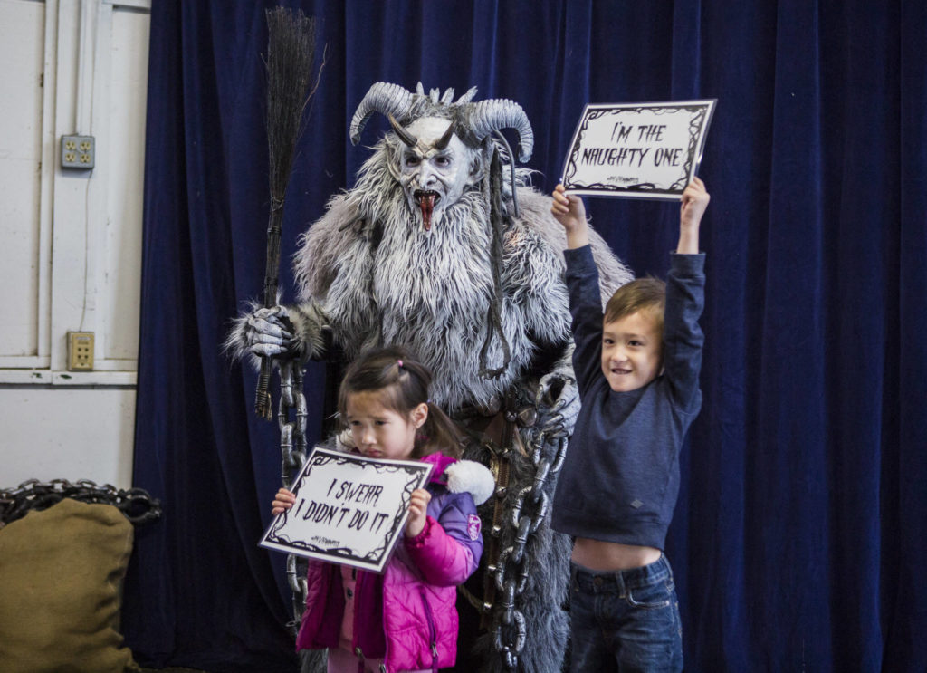 Samantha Breeden, 3, and brother, John Breeden, 5, pose for a photo with Krampus at Oddmall: Emporium of the Weird in Monroe. (Olivia Vanni / The Herald)
