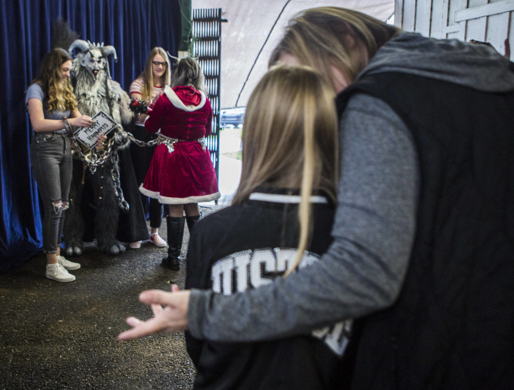 A young girl is convinced by her mother to take a photo with Krampus at Oddmall: Emporium of the Weird in Monroe. (Olivia Vanni / The Herald)
