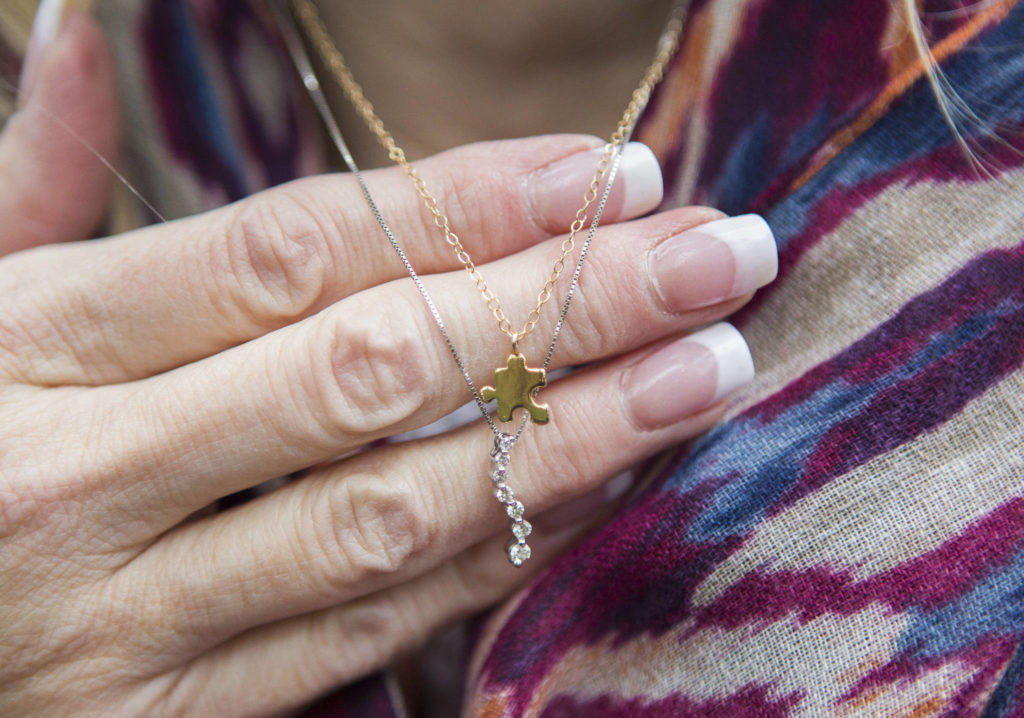 Kelly Howell wears a small gold puzzle piece necklace, given to her by her half-sister, Linda Holt, who wears her own puzzle piece that fits together with Howell’s necklace. (Olivia Vanni / The Herald)
