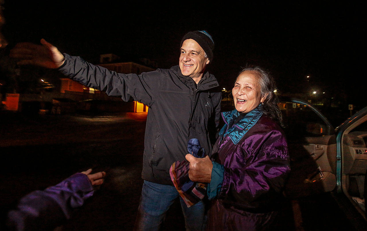 MercyWatch volunteers Duane Schireman and Van Phan greet other helpers at an Everett church parking lot recently before heading out to provide help and supplies to people living on the streets. (Dan Bates / The Herald)