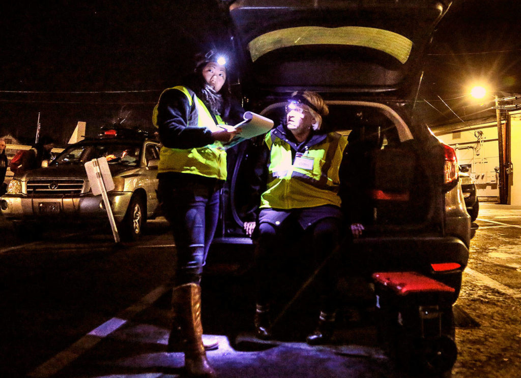 Gail Pyper (seated), a school nurse by day, talks with medical scribe Amanda Dahl near the Everett Public Library recently while on an evening outing with MercyWatch. (Dan Bates / The Herald)
