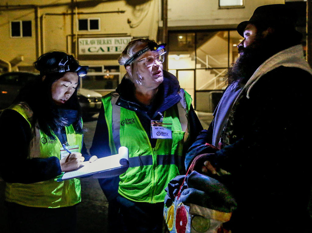 Gail Pyper, a school nurse by day, and her medical scribe Amanda Dahl talk with a man who came to a parking lot on Everett’s Hoyt Avenue. (Dan Bates / The Herald)
