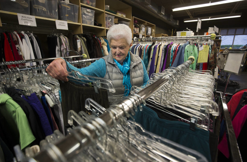 Volunteer Sandi Sharp picks out items to put on sale in a back room at the Assistance League of Everett. (Andy Bronson / The Herald)
