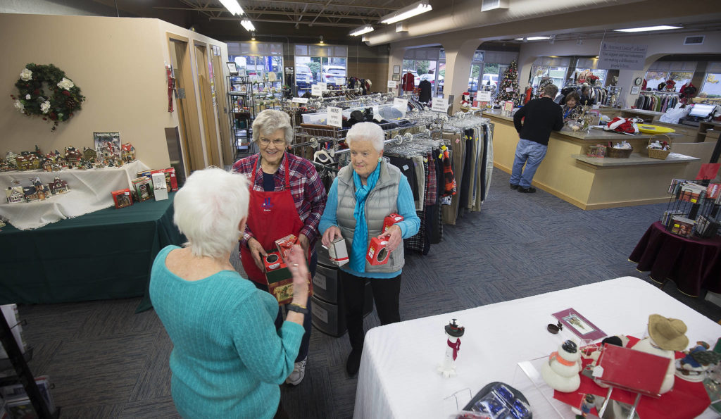 Volunteer Eunice Smith, left, and Sandi Sharp, right, talk with another volunteer in the Assistance League of Everett thrift store. (Andy Bronson / The Herald)
