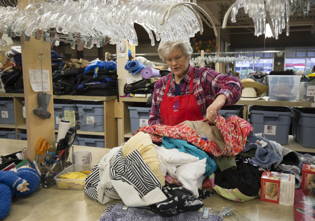 Volunteer Eunice Smith checks for stains and and other defects in clothing donations at the Assistance League of Everett. (Andy Bronson / The Herald)
