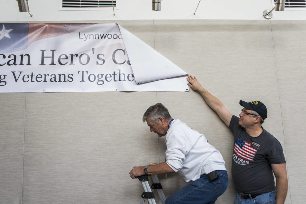 Volunteer Chris Szarek (right) holds up the Hero’s Cafe banner as Steve Pennington climbs the ladder to finish hanging it before the start of the Hero’s Cafe at the Verdant Community Wellness Center on Nov. 26. (Olivia Vanni / The Herald)

