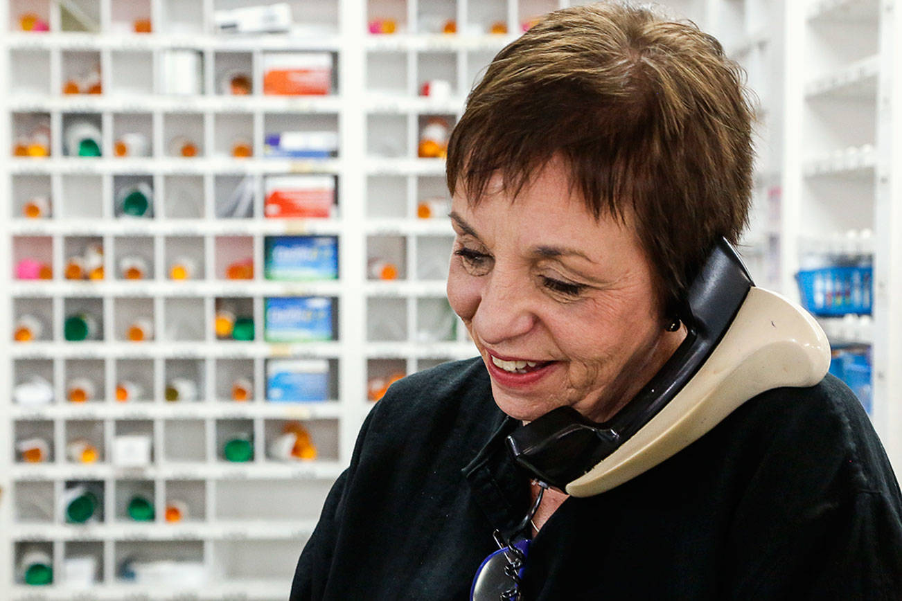 Hilton Pharmacy & Gifts owner Mary Kirkland takes a call at the front counter of her drugstore Monday. Her great-grandfather bought the store 100 years ago this month. Kirkland, a pharmacist, has owned the business since 1984. (Dan Bates / The Herald)