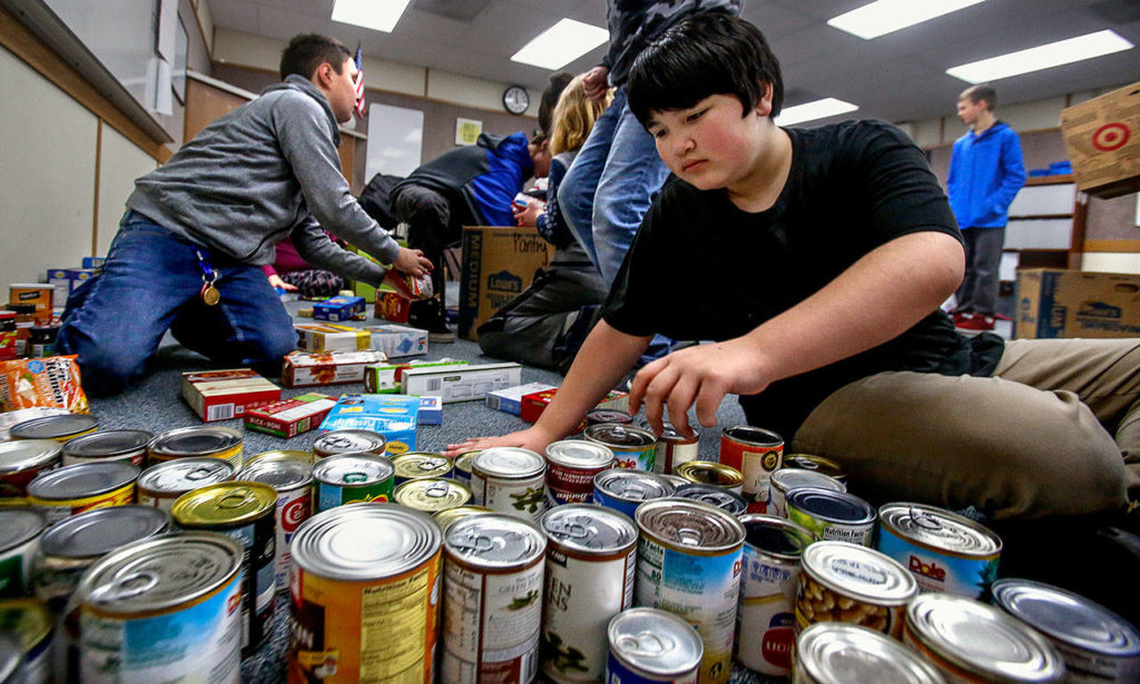 Sixth-grader Jacob Chanthavong sorts canned food and places it in boxes Wednesday at North Middle School in Lake Stevens. His Social Skills class helped with delivery to the Lake Stevens Community Food Bank. (Dan Bates / The Herald)
