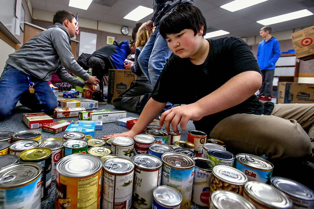 Sixth-grader Jacob Chanthavong sorts canned food and places it in boxes Wednesday at North Middle School in Lake Stevens. His Social Skills class helped with delivery to the Lake Stevens Community Food Bank. (Dan Bates / The Herald)