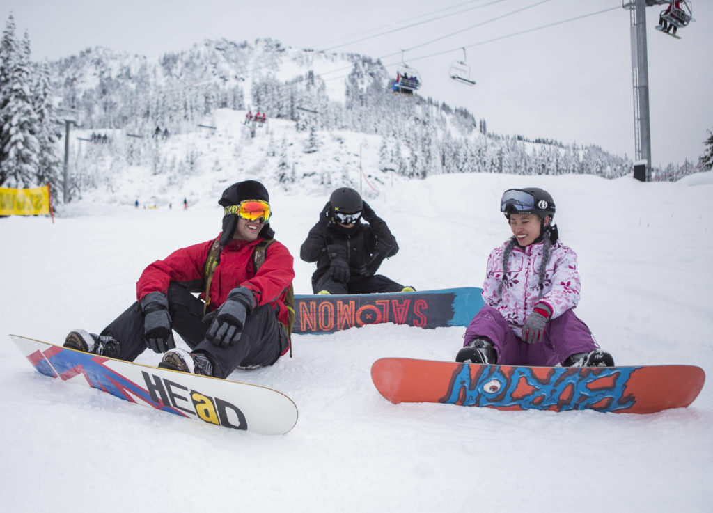 From left, Shawn Poole, Danny Nuon and Vy Bui take a break while snowboarding the Daisy run at Stevens Pass on Wednesday. It was Bui’s first time snowboarding. (Olivia Vanni / The Herald)
