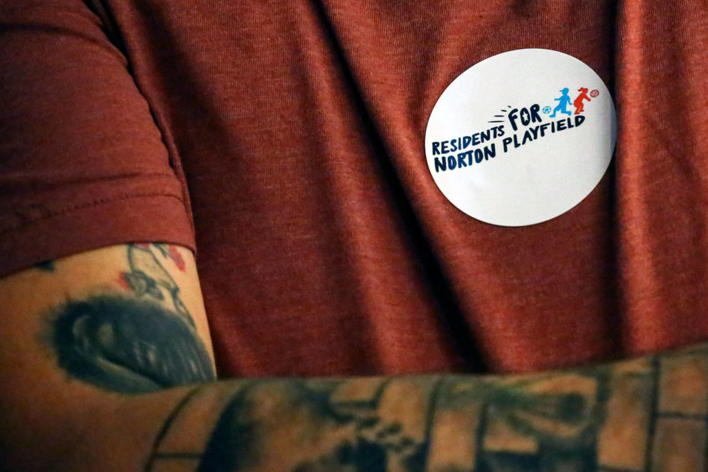 Community members wear stickers against a proposal Wednesday evening at Everett City Hall. (Kevin Clark / The Herald)
