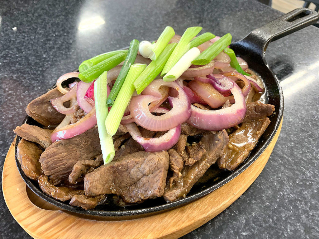 The sizzling platter of bistek tagalog is meant to be shared by two or three people. (Evan Thompson / The Herald)
