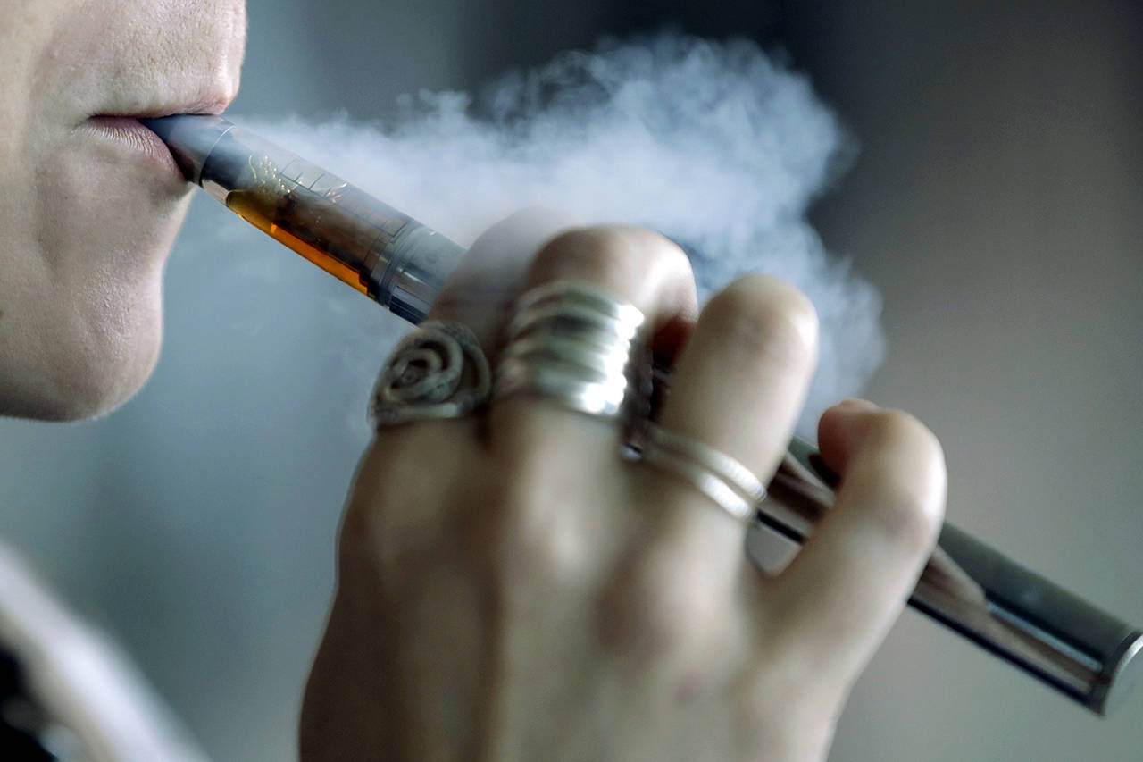 In this Oct. 4 photo, a woman using a vaping device exhales a puff of smoke in Mayfield Heights, Ohio. (AP Photo/Tony Dejak, File)