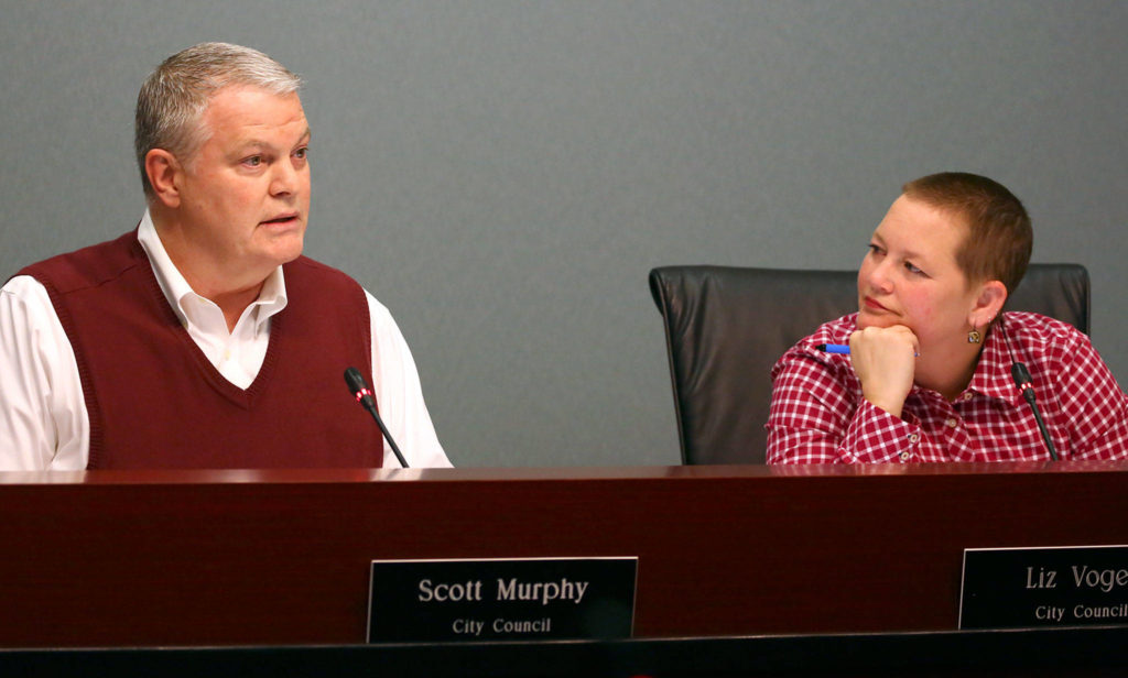 Councilmember Scott Murphy offers his comments with Liz Vogeli looking on Wednesday evening at the Everett City Hall. (Kevin Clark / The Herald)
