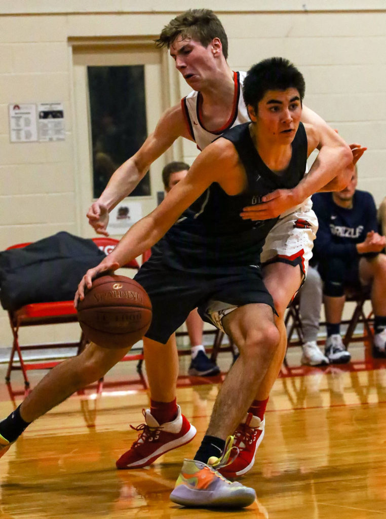 Glacier Peak’s Tucker Molina drives the baseline with King’s Jordan Hansen defending Friday evening at King’s School in Shoreline. The Grizzles won 58-53. (Kevin Clark / The Herald)
