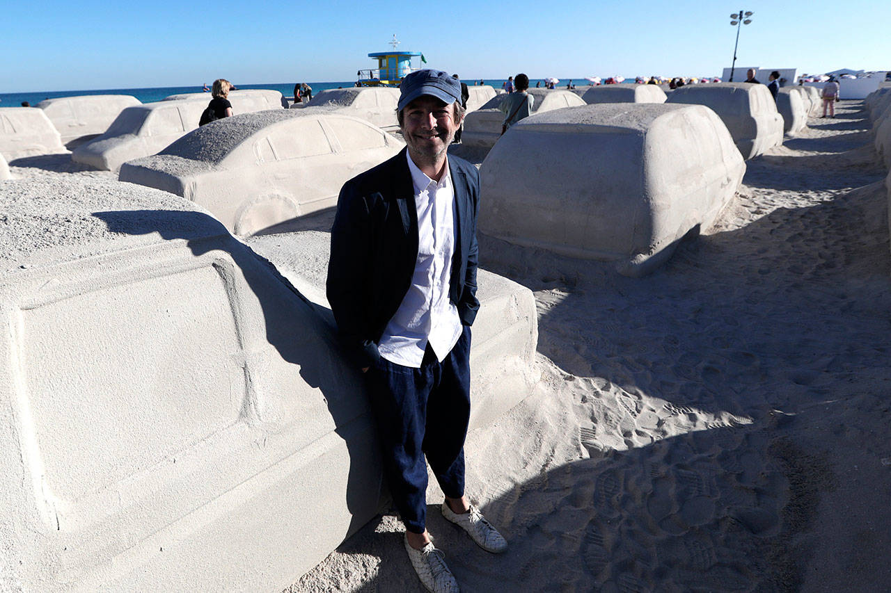 Artist Leandro Erlich, of Argentina, poses with his work featuring cars sculpted in sand stuck in a traffic jam. (AP Photo/Lynne Sladky)