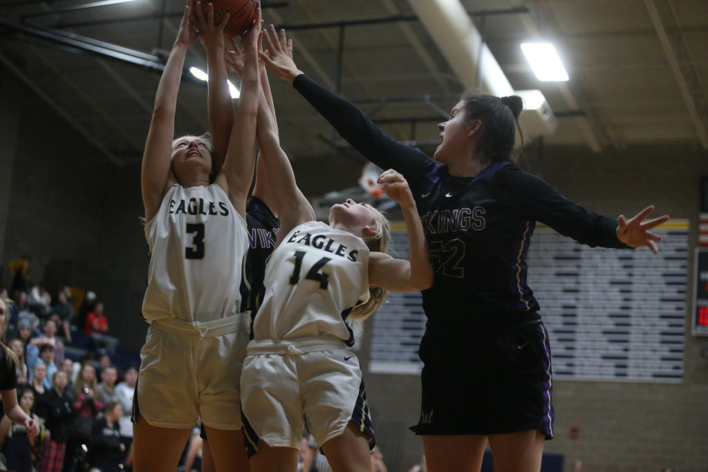 Arlington’s Abby Schwark and Keira Marsh reach for a rebound against Lake Stevens’ Camille Jentzschas the Arlington Eagles lost to the Lake Stevens Vikings 57-54 in a girls’ basketball game on Friday, Dec. 6, 2019 in Arlington, Wash. (Andy Bronson / The Herald)
