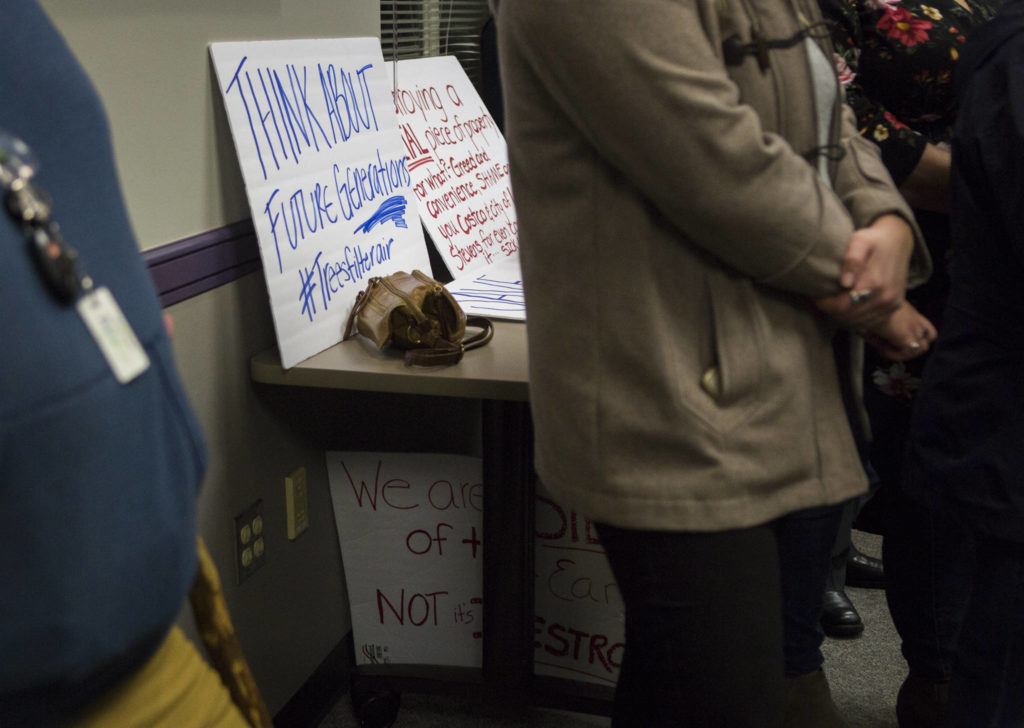 Signs against a Costco being built sit on a table during the Lake Stevens City Council meeting on Tuesday. (Olivia Vanni / The Herald)
