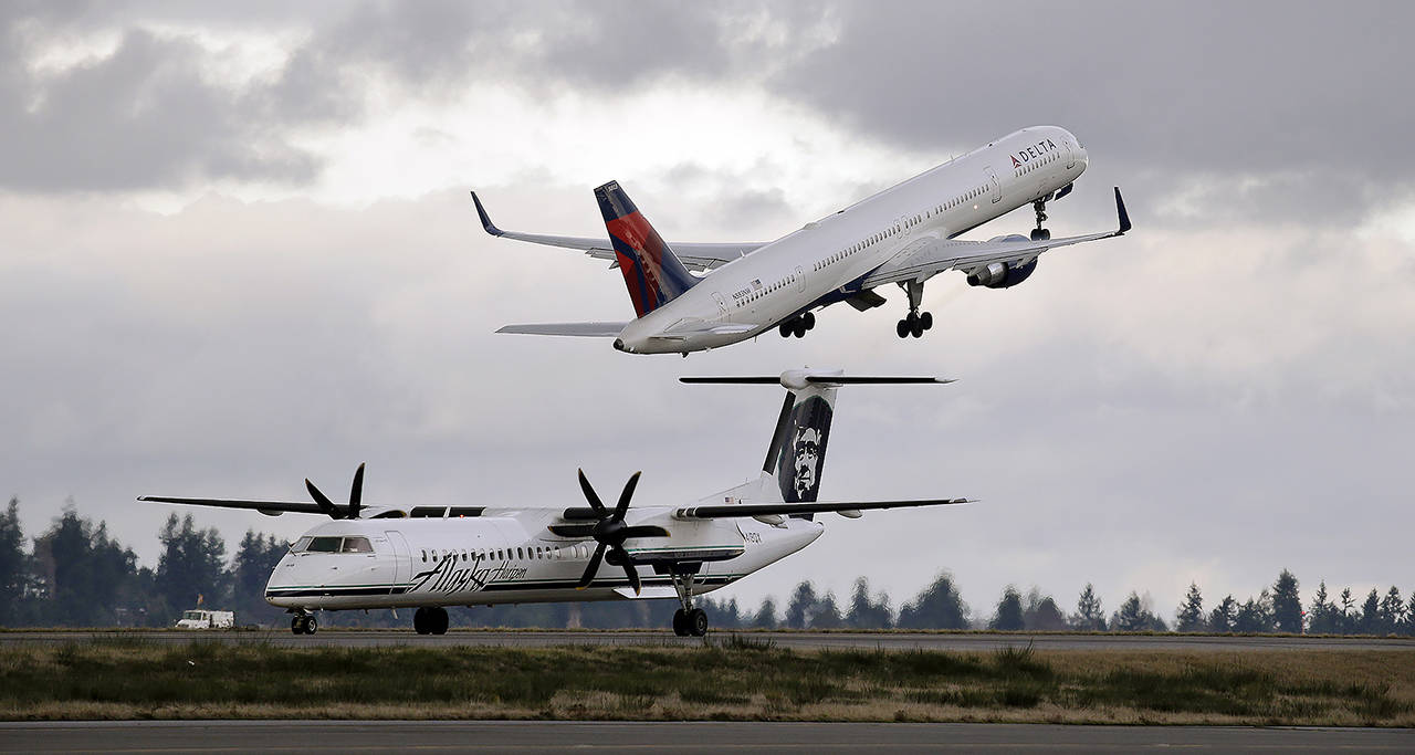 A Delta jet takes off in view of an Alaska Airlines plane that just landed at Seattle-Tacoma International Airport in 2015. (AP Photo/Elaine Thompson, file)