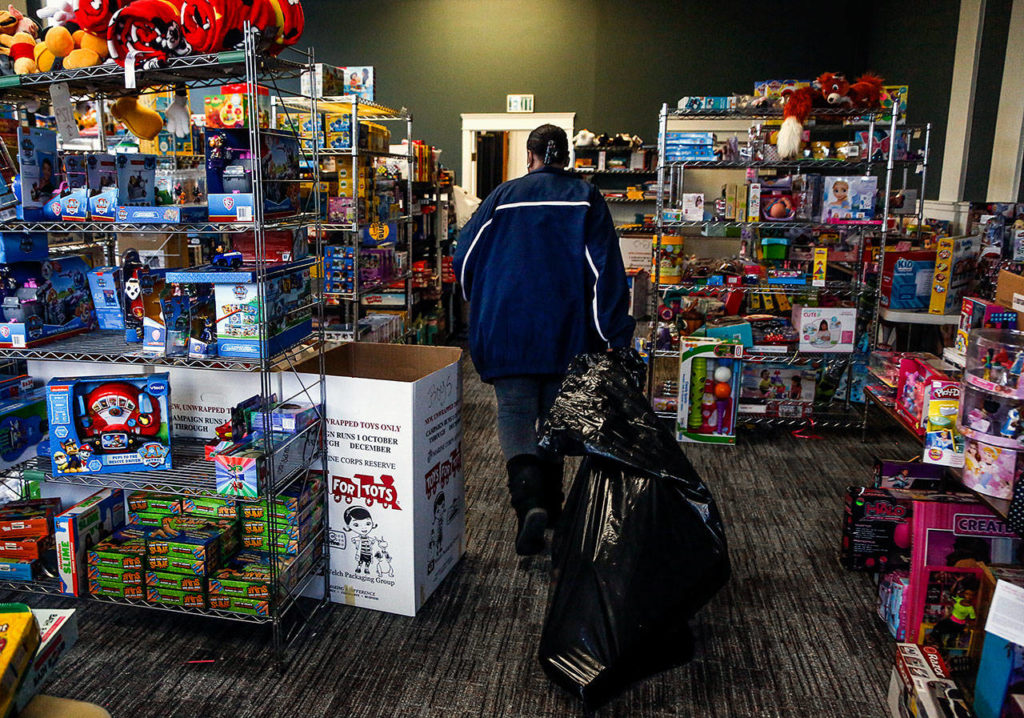 Having found what she was looking for, Mary Butler heads out of the Toys for Tots distribution room at Everett’s Foundation Church, dragging a large bag behind her. (Dan Bates / The Herald)
