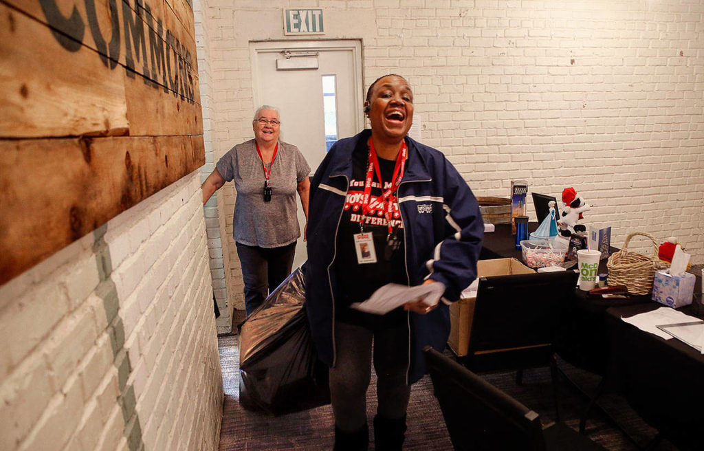 Like Santa with his sack of toys, Mary Butler brings a bag of gifts and a joyful smile to a family being served by Toys for Tots on Thursday. Volunteer Sharon Argle, who helped with toy selection, is behind her. (Dan Bates / The Herald)
