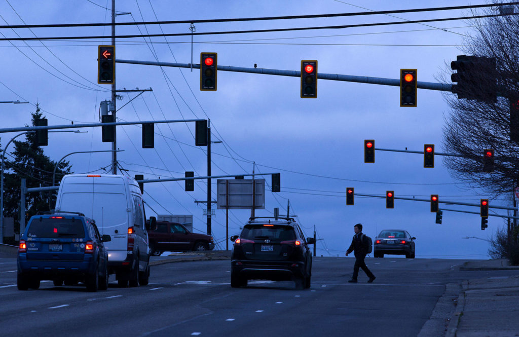 A man crosses the road under stoplights at Casino Road and Evergreen Way on Friday, Dec. 13, 2019 in Everett, Wash. The lights at Casino Road and Evergreen Way are being considered for controversial red-light traffic cameras. (Andy Bronson / The Herald)
