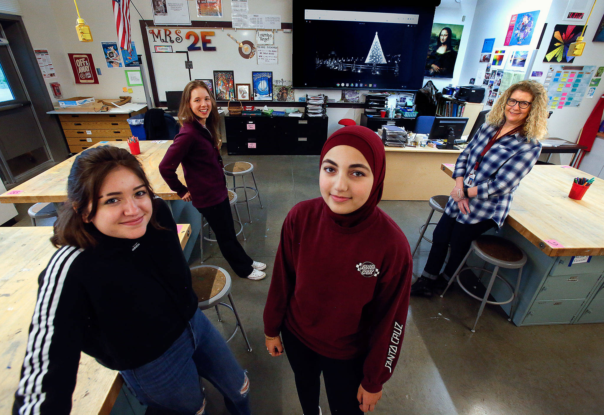 Art students at Cavelero Mid High School, Ivonne Salazar, 15 (left) and Maryam Hasan, 14 (center) join teachers Karen Towey (back right) and Kylen Fountain to talk about creating ornaments for the National Christmas Tree project. An image of the tree, located near the White House, is displayed on a screen in the classroom. (Dan Bates) / The Herald)