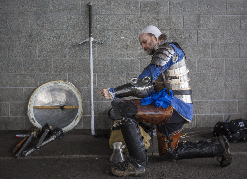 Live action role player Douglas West kneels while donning his armor for combat practice. (Olivia Vanni / The Herald)
