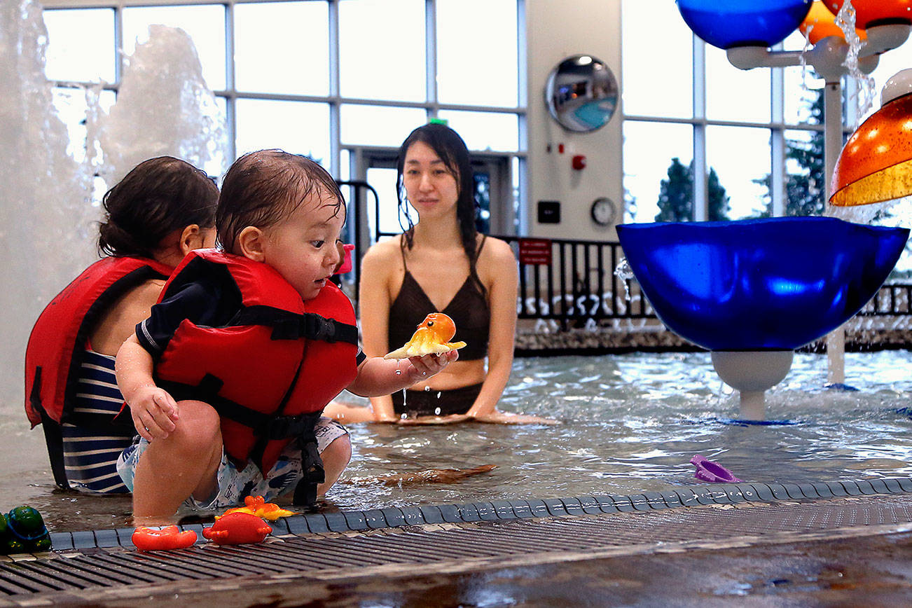 Odin Frye, 2, plays near his sister Emma, 4, and his mom, Saeko Frye, in the recreation pool at the new Everett Family YMCA. Odin found a colorful octopus in the shallows of the children’s pool, which has a zero-entry “beach.” (Dan Bates / The Herald)