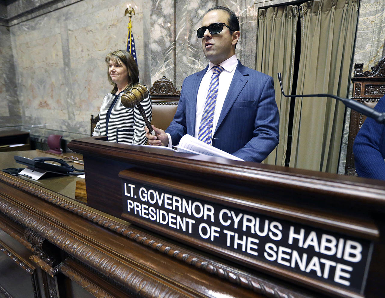 Cyrus Habib (right) holds the gavel as he stands at the Senate chamber dais next to Senate Counsel Jeannie Gorrell (left) in January 2017, about a week before being sworn in as Washington’s Lieutenant Governor. (AP Photo/Ted S. Warren, file)