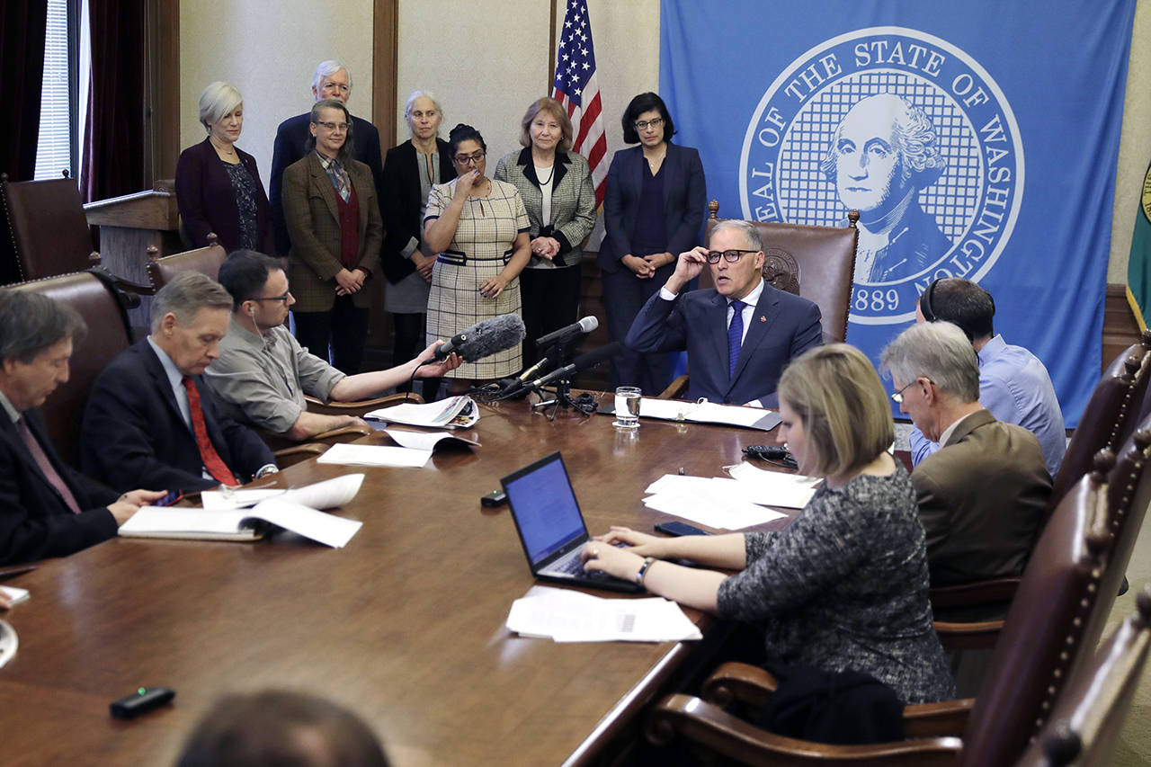 Washington Gov. Jay Inslee (seated center) talks to reporters about his proposed supplemental state budget Wednesday at the Capitol in Olympia. (AP Photo/Ted S. Warren)