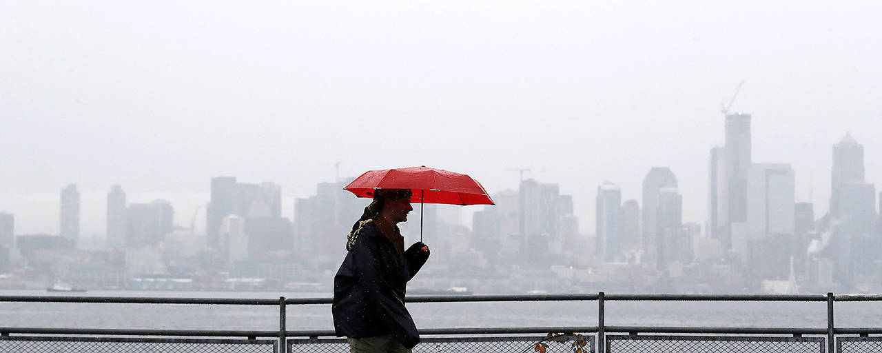 A pedestrian walks along a waterfront as downtown Seattle is partially hidden in a steady rain on Nov. 18. Heavy rain is expected in the region starting Thursday night. (AP Photo/Elaine Thompson, file)