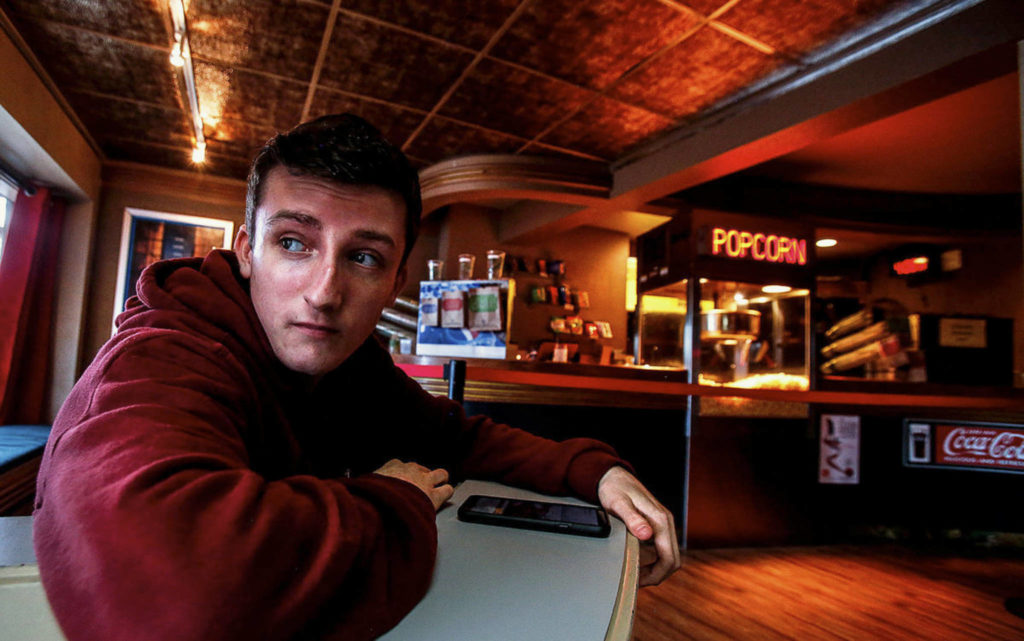 From the Edmonds Theater’s distinctive Art Deco lobby, employee Jack Eccleshall, 18, glances out the window. (Dan Bates / The Herald)