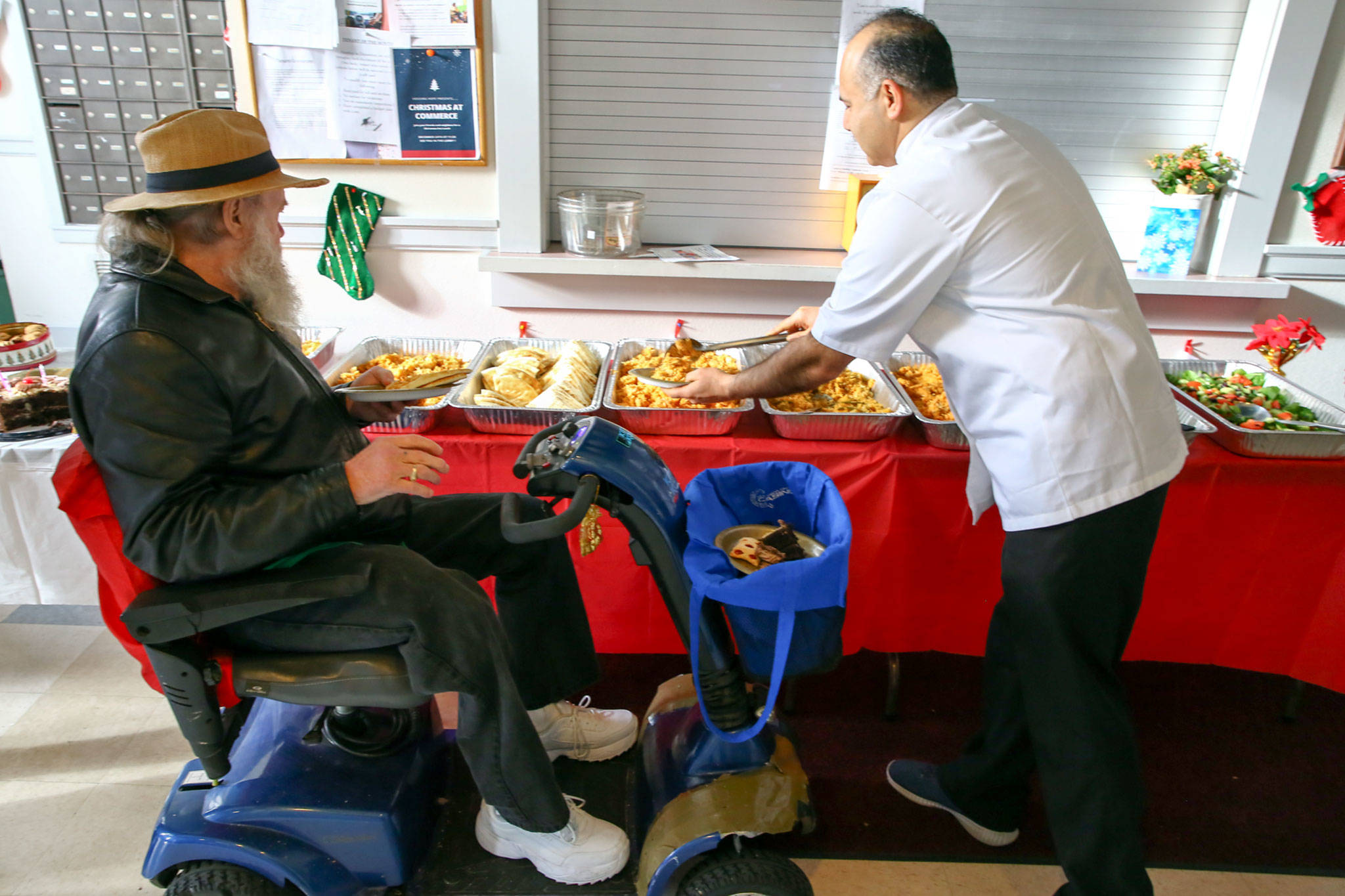 Jerry Johnson (left) and Shahzad Raja help themselves the spread laid out by Raja on Tuesday morning at Housing Hope in Everett. (Kevin Clark / The Herald)