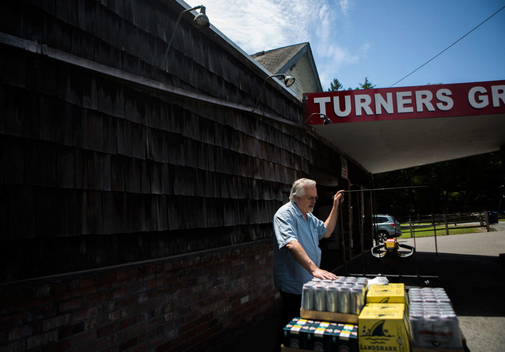 Doug Turner chats with his beer delivery man outside of his grocery store on July 12 in Lake Stevens. (Olivia Vanni / The Herald)
