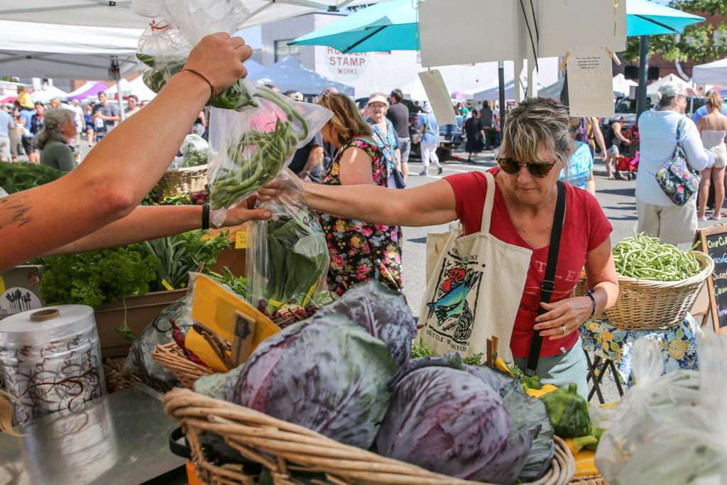 Nancy Cody shops at a produce stand Aug. 4 at Everett Farmers Market. (Kevin Clark / The Herald)

