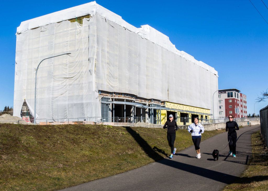 Joggers on the Interurban Trail run past a Hilton Garden Inn under construction on March 1 in Lynnwood. (Olivia Vanni / The Herald)
