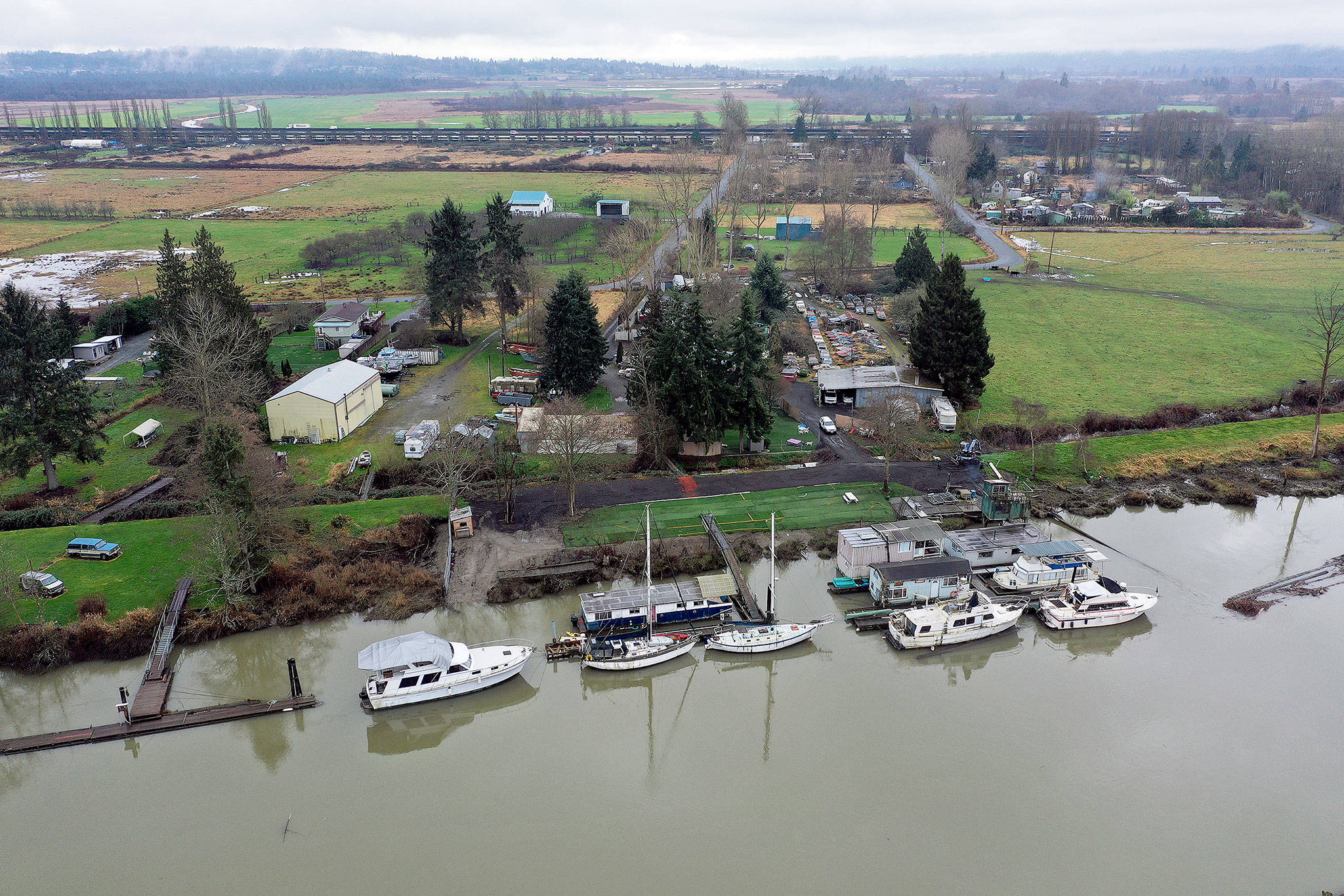 Boats docked along the Snohomish River on the north side of Ebey Island, just south of Spencer Island Park. This view is looking south, with the U.S. 2 trestle in the background. (Chuck Taylor / The Herald)