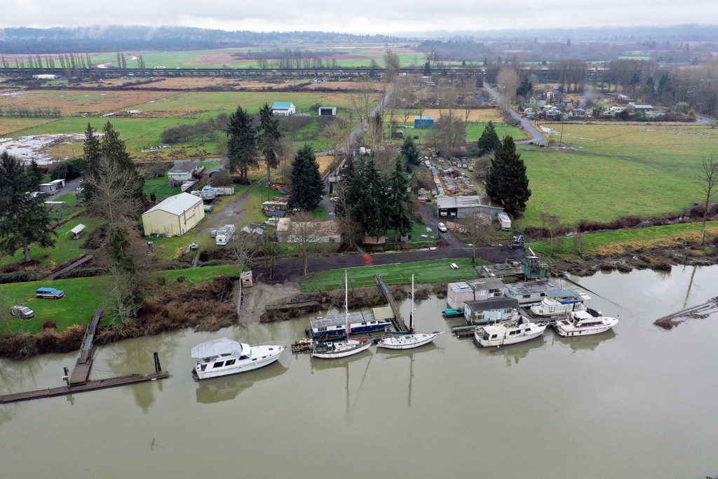 Boats docked along the Snohomish River on the north side of Ebey Island, just south of Spencer Island Park. This view is looking south, with the U.S. 2 trestle in the background. (Chuck Taylor / The Herald)
