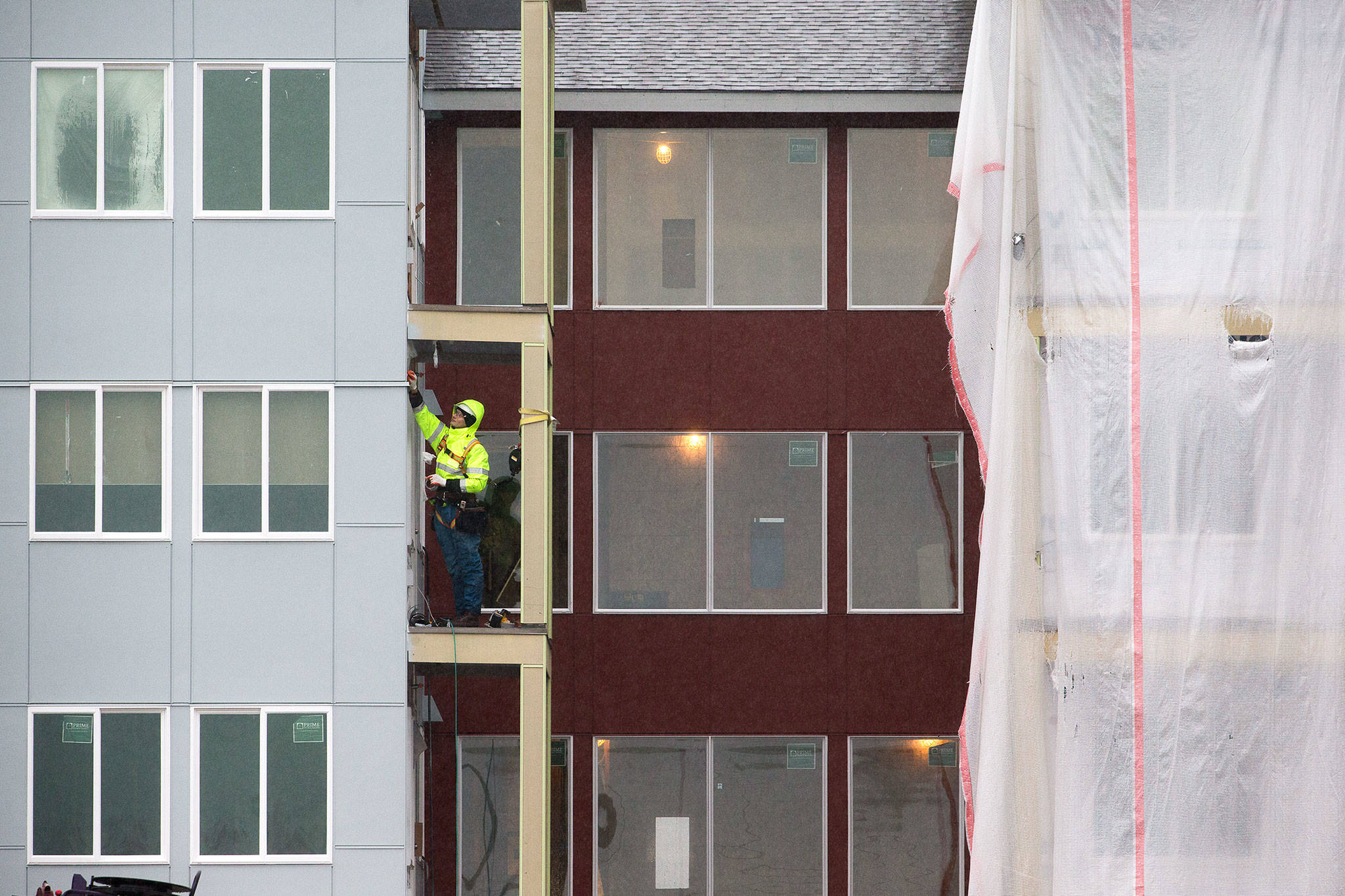 A man works on a balcony Monday at the Cedar Pointe Apartments, a 255-unit complex for adults 55 and older, at 17309 40th Ave. in Arlington. (Andy Bronson / The Herald)