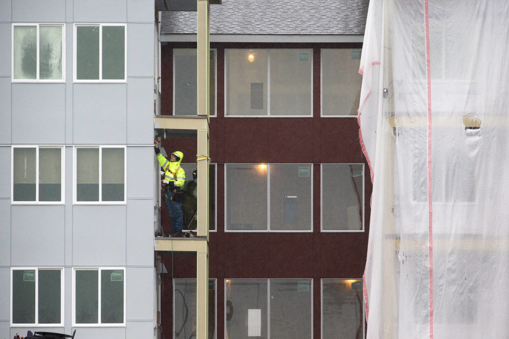 A man works on a balcony Monday at the Cedar Pointe Apartments, a 255-unit complex for adults 55 and older, at 17309 40th Ave. in Arlington. (Andy Bronson / The Herald)
