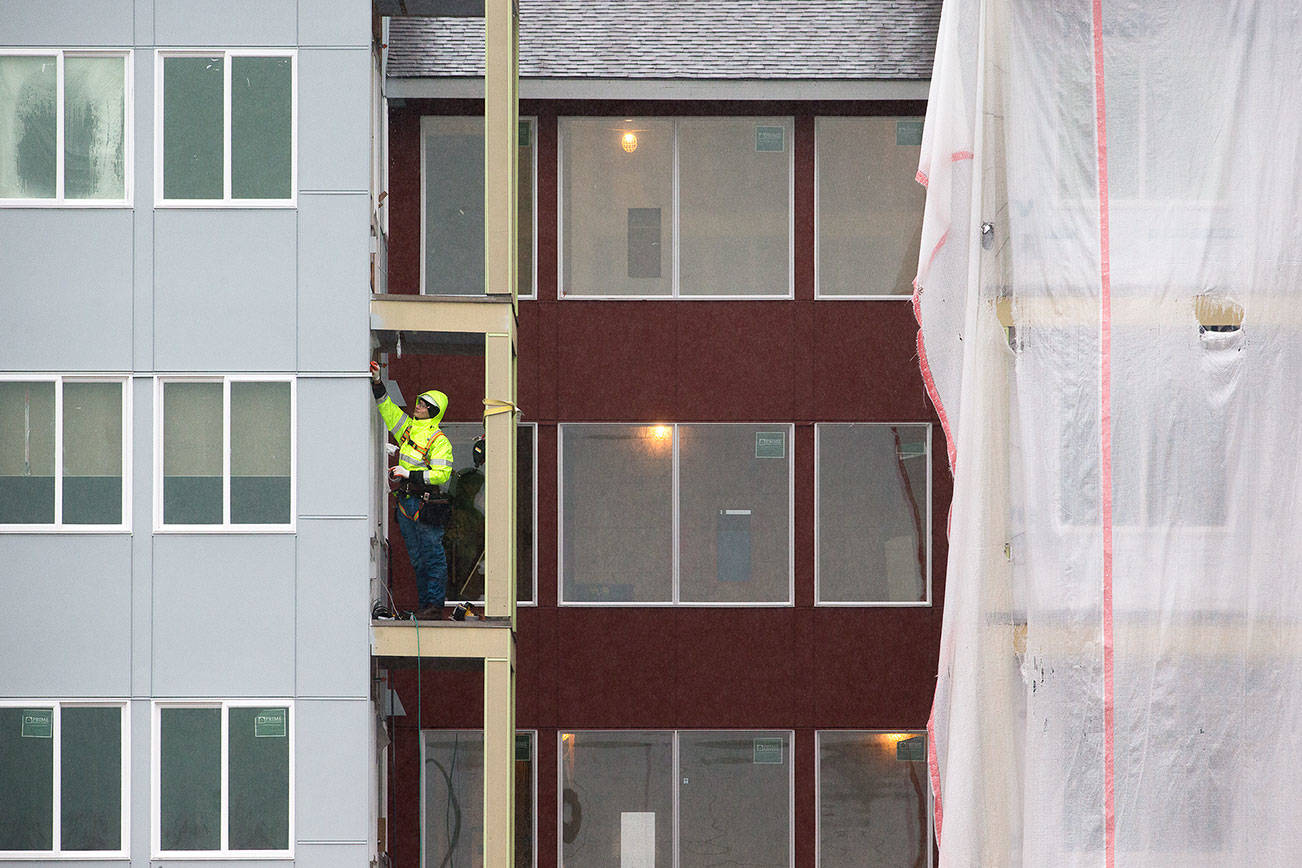 A man works on a balcony Monday at the Cedar Pointe Apartments, a 255-unit complex for adults 55 and older, at 17309 40th Ave. in Arlington. (Andy Bronson / The Herald)