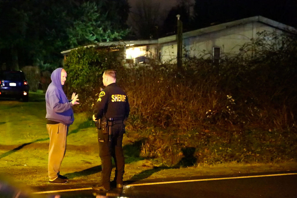 Adam Fortney (right) talks to with a resident about an abandoned car in Mukilteo on December 31, 2019. (Kevin Clark / The Herald)
